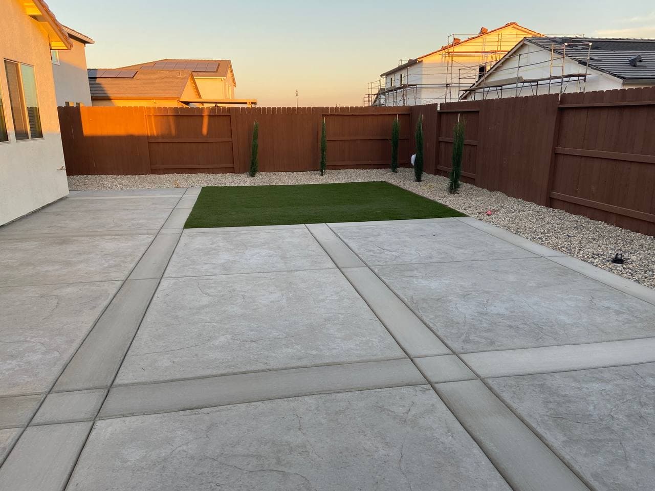 Gray stamped concrete patio with a turf inset at dusk
